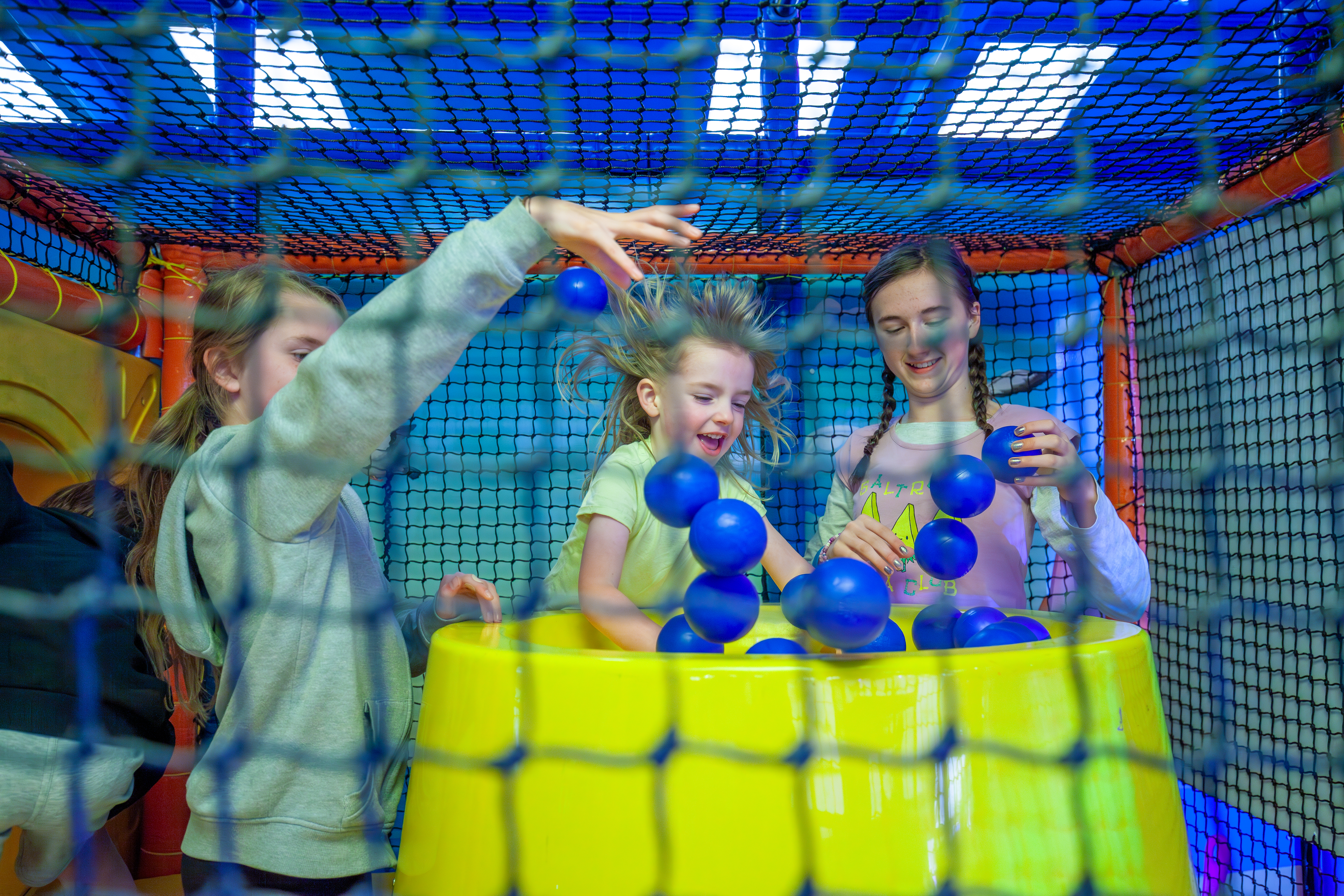 And image of three girls playing with some floating balls in a soft play indoor centre 