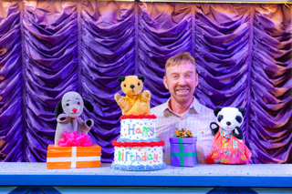 Photo of Richard Cadell, Sooty and Sweep with a birthday cake that says happy birthday 