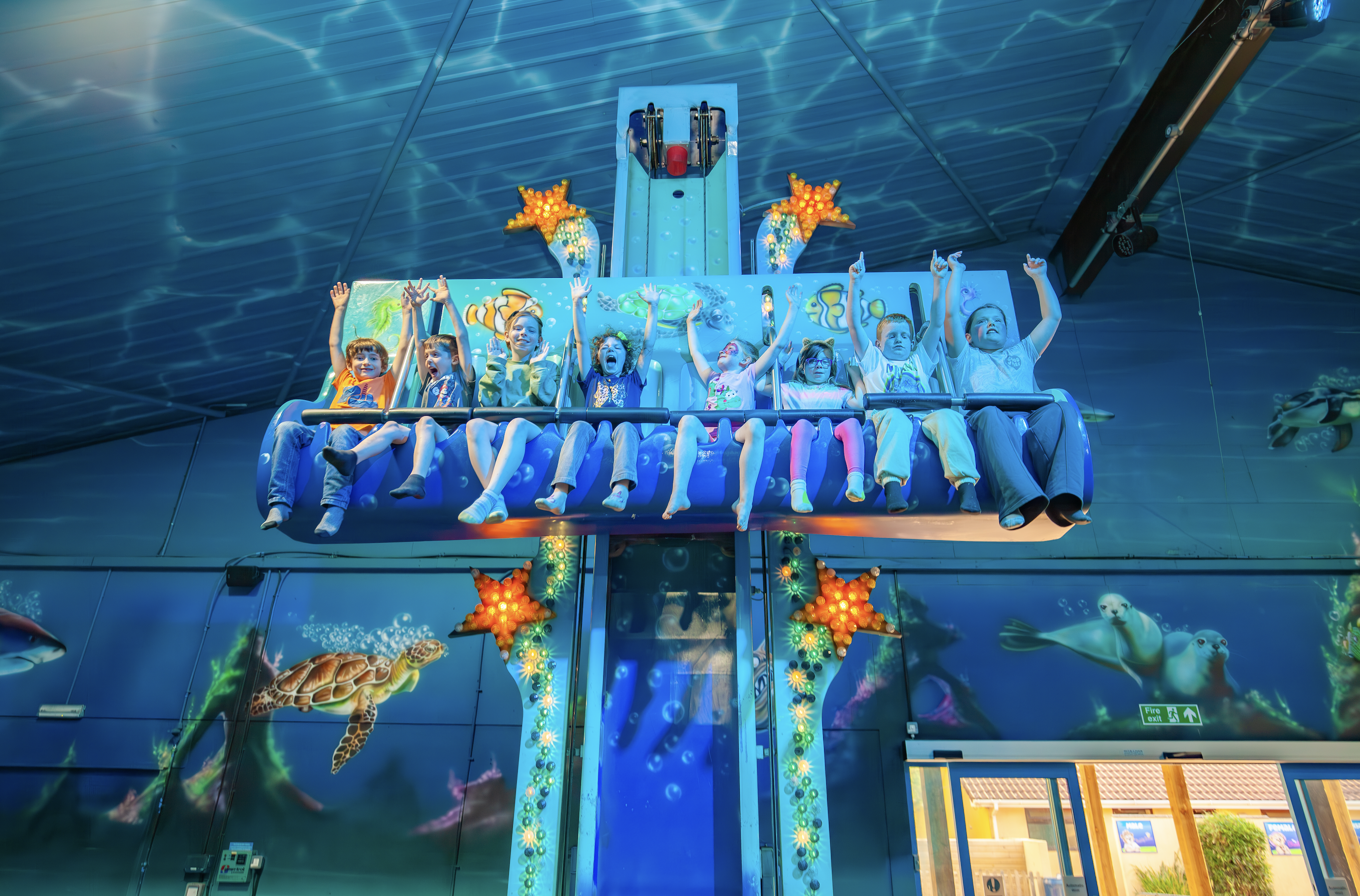 Kids having fun on a blue dolphin themed drop tower ride