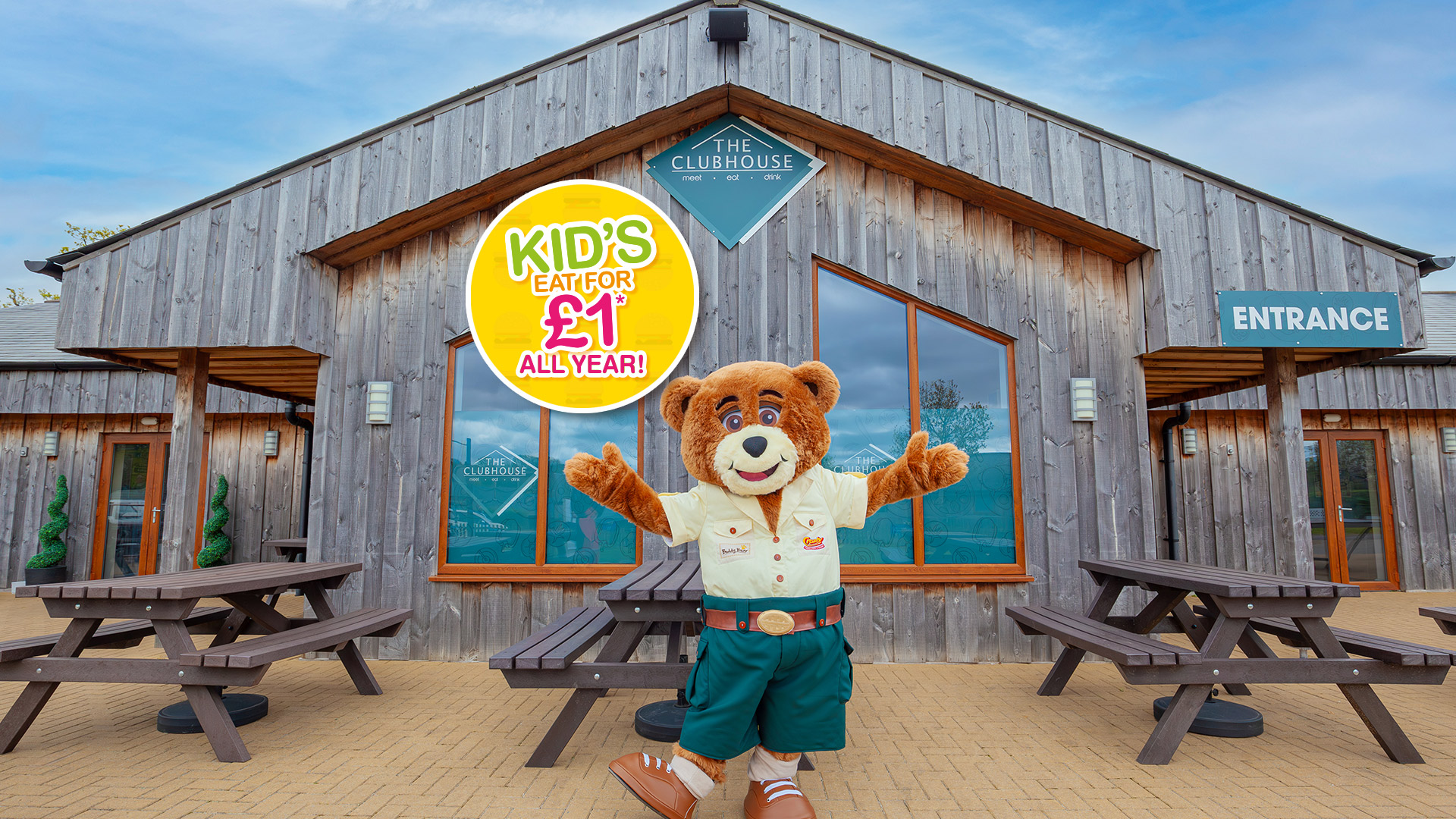 Image of Buddy bear the mascot outside the clubhouse with Kids eat for just £1 sticker 