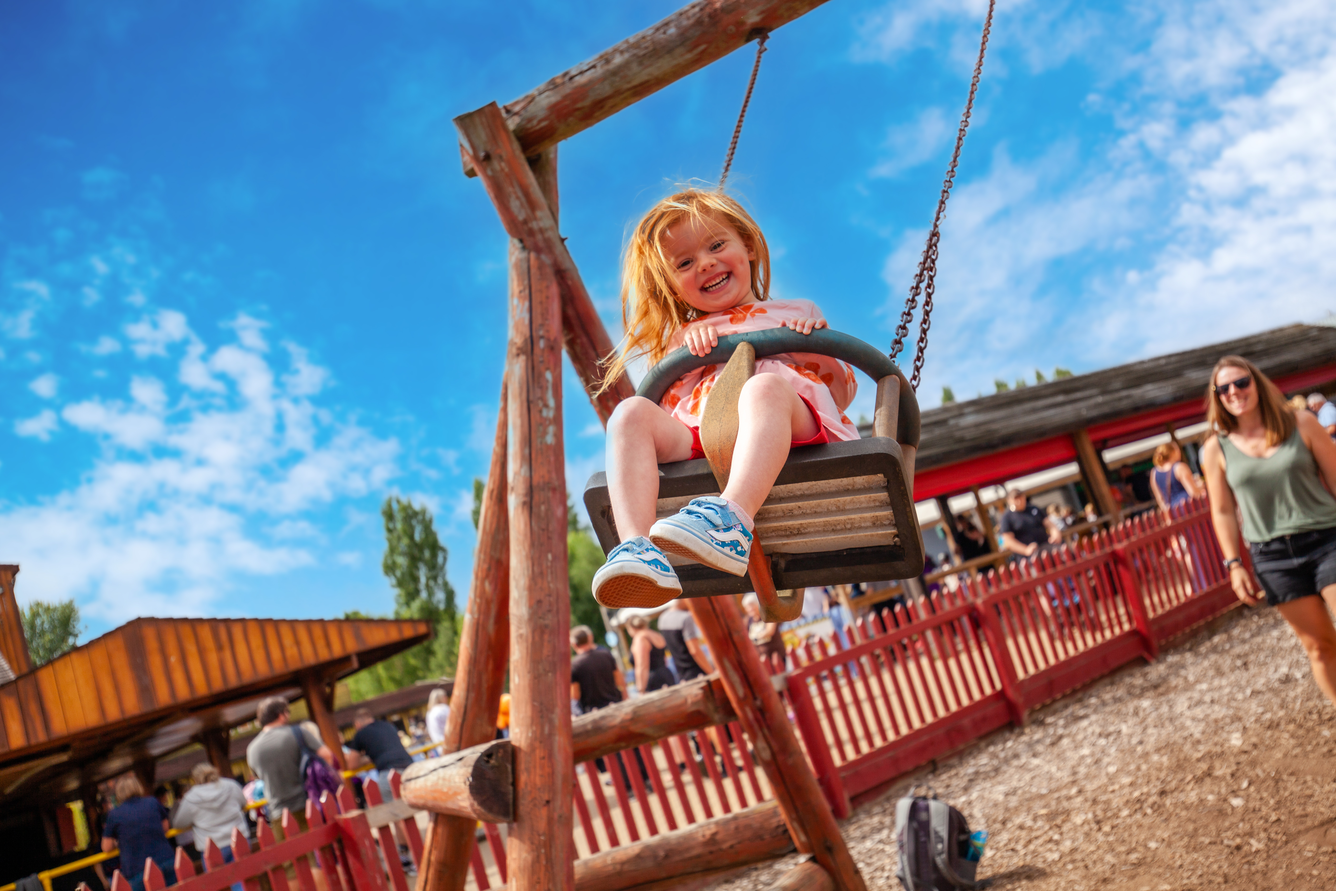 An image of a girl on an outdoor swing with blue skies 