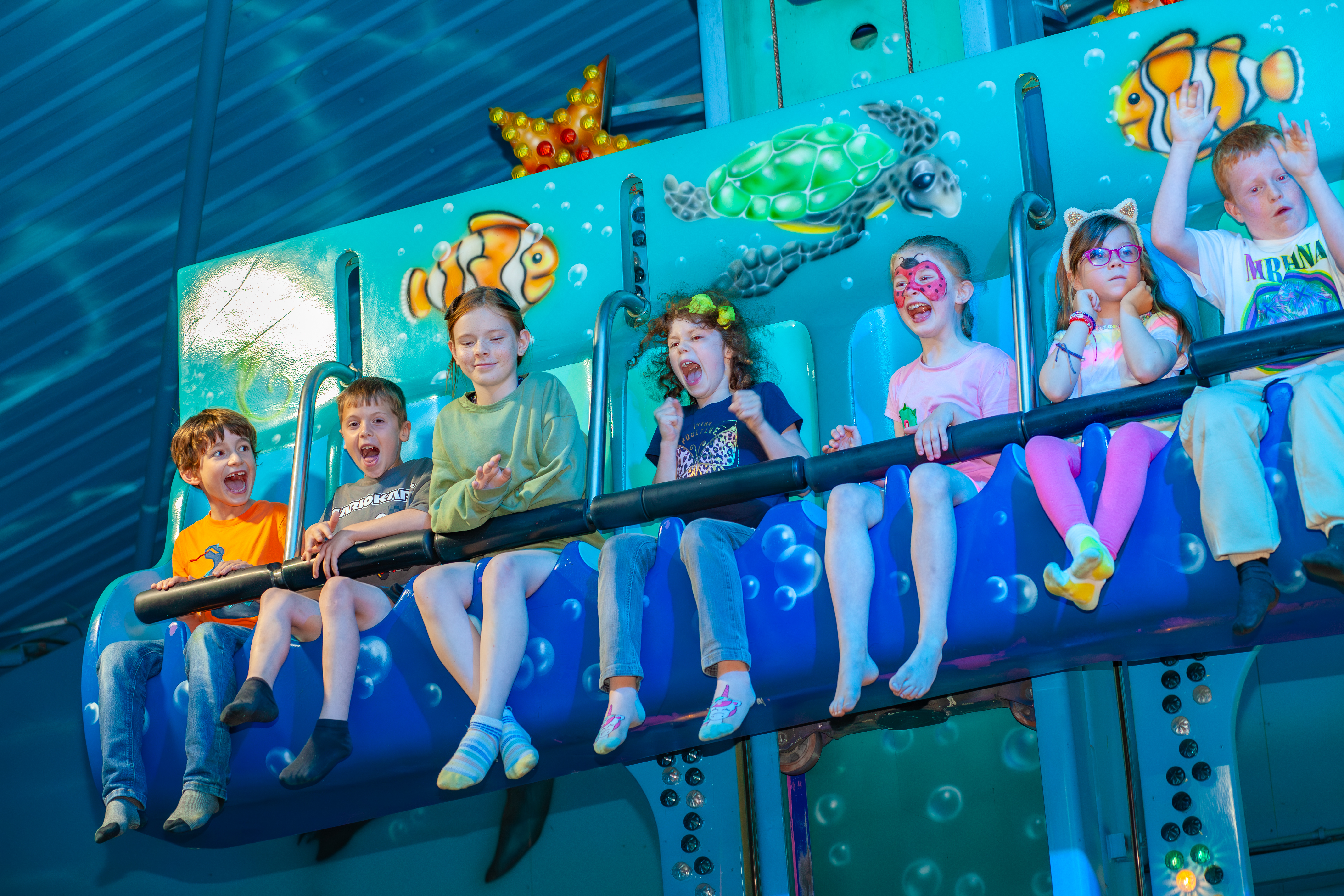 And image of a group of children on a dolphin themed indoor drop ride 